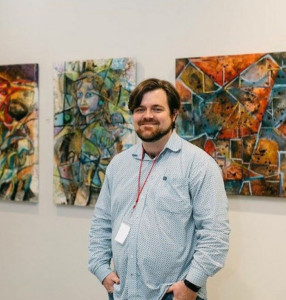 A picture of Jason Stallings at a private art opening in Dallas Texas in 2017 with a few of his paintings.