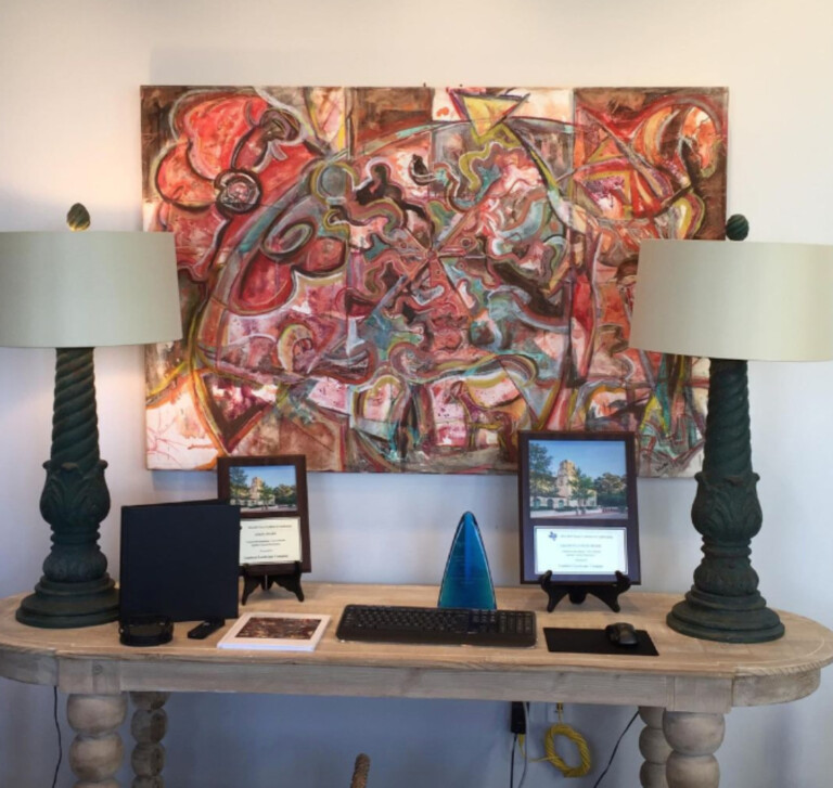The sold "Garden Composition #1" painting hanging in the corporate board room of Lamberts Landscape design in Dallas, Texas. The painting is primarily made up if reds and yellows and some hints of green.